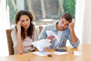 Frustrated couple sitting at table looking at bills